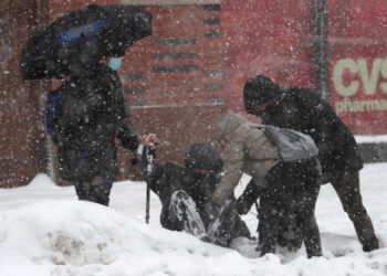 People help a man who fell in snow along 125th street in Manhattan during a winter storm in New York City, New York, U.S., February 1, 2021. REUTERS/Mike Segar