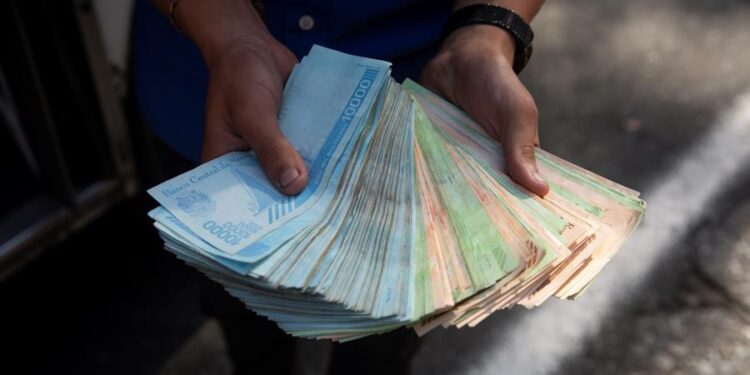 Un transportista muestra un fajo de bolívares, el 12 de marzo de 2021, en Caracas (Venezuela). Venezuela estrena un flamante billete. Marca un millón de bolívares en su anverso pero, en el reverso, los venezolanos se preguntan qué se compra con él y se responden con contundencia: apenas nada. Parece abocado a pagar el pan o los billetes de autobús antes de caer en los cuadernos de coleccionistas. EFE/ Rayner Peña R.