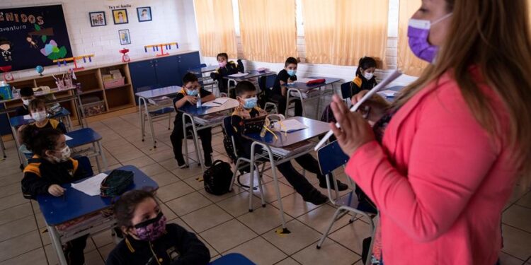 Una docente es vista con un grupo de alumnos durante una clase en el Colegio Polivalente Patricio Mekis durante la primera jornada de inicio del curso escolar 2021, el 1 de marzo de 2021 en Santiago (Chile). EFE/Alberto Valdés