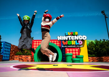 In this picture taken on March 17, 2021, fans of Universal Studio Japan pose at the entrance of the Super Nintendo World, during a media preview of the theme park in Osaka. (Photo by Philip FONG / AFP)
