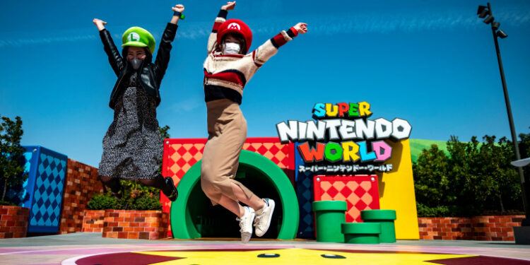 In this picture taken on March 17, 2021, fans of Universal Studio Japan pose at the entrance of the Super Nintendo World, during a media preview of the theme park in Osaka. (Photo by Philip FONG / AFP)