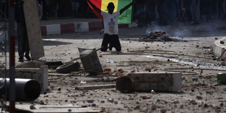 A demonstrators holds a Senagalese during protests at the  Cheikh Anta Diop University campus in Dakar, Senegal,  against the arrest of opposition leader and former presidential candidate Ousmane Sonko Thursday, March 4, 2021. (AP Photo/Leo Correa)