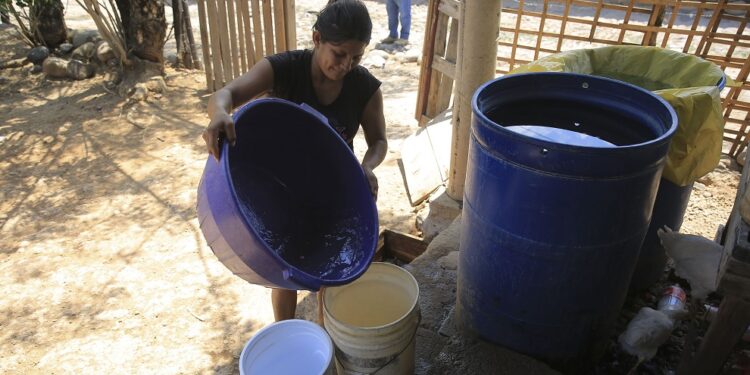 ACOMPAÑA CRÓNICA: HONDURAS AGUA - TG1013. CHOLUTECA (HONDURAS), 23/04/2018.- Fotografía del 13 de abril de 2018 de una mujer almacenando agua en envases plásticos para su uso domiciliario en el sector de Apacilagua, unos 30 kilómetros al este de Choluteca (Honduras). La ciudad de Choluteca, en el sur de Honduras, vuelve a padecer una fuerte sequía que afecta a sus 200.000 habitantes y al sector agrícola, al no poder utilizar como quisiera el agua del río Choluteca, que desde hace años esta bajo una concesión de uso privado. Durante los meses de abril y mayo, el río Choluteca se mantiene prácticamente seco, lo que impacta negativamente en las necesidades de agua de los habitantes, limita la producción agrícola y eleva los costos de actividades como la caña de azúcar que, justamente en esos meses, requiere de importantes cantidades de agua para riego. EFE/Gustavo Amador