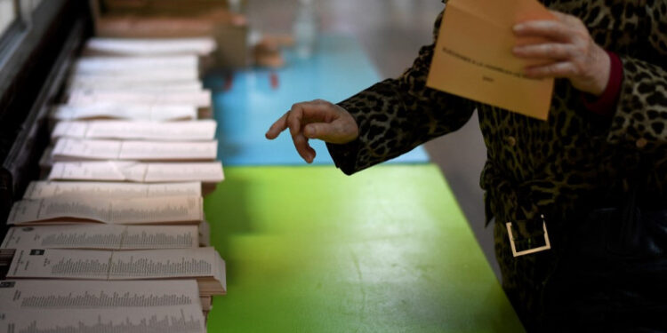 A woman picks up a ballot at a polling station in Madrid during the Madrid regional elections on May 4, 2021. - Madrid is voting in an early regional election the incumbent conservative Popular Party is expected to win comfortably, dealing a blow to Spain's Socialist prime minister. (Photo by OSCAR DEL POZO / AFP)