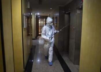 CARACAS, VENEZUELA - JULY 20: A member of the medical staff disinfects the corridors of the hotel where COVID-19 patients are staying during week 19 of radical quarantine on July 20, 2020 in Caracas, Venezuela. To manage hospital occupation rates, Venezuelan government has 4,000 hotel rooms nationwide to host and isolate patients of COVID-19 with no or mild symptoms. The Milenio hotel, in the Chaguaramas area, has 60 rooms and is now hosting 61 patients. They stay in single or double rooms with air conditioning, cable TV and internet service. Three groups of doctors rotate in shifts of three days and stay at the hotel. Patients are tested every two or three days and receive doses of Chloroquine and Azithromycin. There is international concern about the real capacity of the government of Nicolas Maduro to control the pandemic due to the health, social and economic crisis the country is going through. According to Johns Hopkins University, Venezuela has 12,334 positive cases (half of them already recovered) and 116 reported deaths. (Photo by Leonardo Fernandez Viloria/Getty Images)