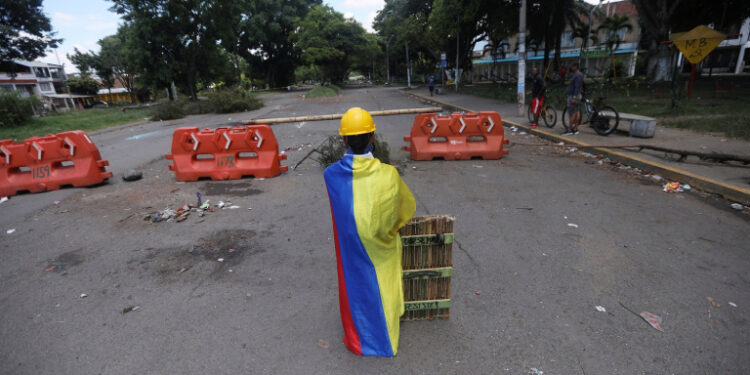 Manifestante de primera línea envuelto en bandera de Colombia en barricada, Cali, Colombia, 13 mayo 2021.
REUTERS/Luisa González
