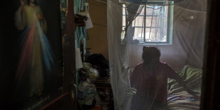 A woman rests wrapped in a mosquito net to protect herself from mosquitos which can transmit malaria at her house in Barcelona, Anzoategui State, Venezuela, on March 16, 2021. - In Venezuela there are people who had malaria up to 20 times. The proliferation, with epicentre in the southern mining region, is a paradox in a country which became the first to eradicate the illness caused by the Plasmodium parasite in 1961. (Photo by Pedro Rances Mattey / AFP)