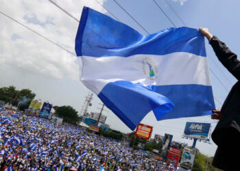 A man waves a Nicaraguan flag as people participate in a demonstration called the "March of the Flowers" remembering the children killed during the last two-months violence, in Managua, Nicaragua, Saturday, June 30, 2018. The Central American nation has been rocked since April 19 by daily chaos as protesters maintaining roadblocks and demanding Ortega's ouster are met by a heavy-handed crackdown by security forces and allied civilian groups. (AP Photo/Alfredo Zuniga)