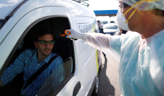 A health worker takes the temperature of a driver for precaution due to coronavirus disease (COVID-19), in Buenos Aires, Argentina March 19, 2020. REUTERS/Agustin Marcarian