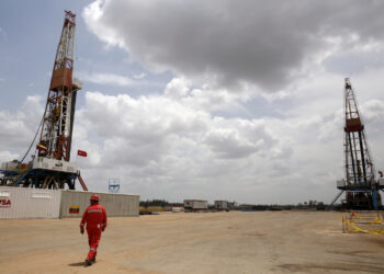 FILE PHOTO: An oilfield worker walks next to drilling rigs at an oil well operated by Venezuela's state oil company PDVSA, in the oil rich Orinoco belt, April 16, 2015.. REUTERS/Carlos Garcia Rawlins/File Photo