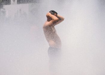 A man cools off in the Salmon Street springs fountain in Portland, Oregon on June 28, 2021, as a heatwave moves over much of the United States. - Swathes of the United States and Canada endured record-setting heat on June 27, 2021, forcing schools and Covid-19 testing centers to close and the postponement of an Olympic athletics qualifying event, with forecasters warning of worse to come. The village of Lytton in British Columbia broke the record for Canada's all-time high, with a temperature of 46.6 degrees Celsius (116 Fahrenheit), said Environment Canada. (Photo by Kathryn Elsesser / AFP)