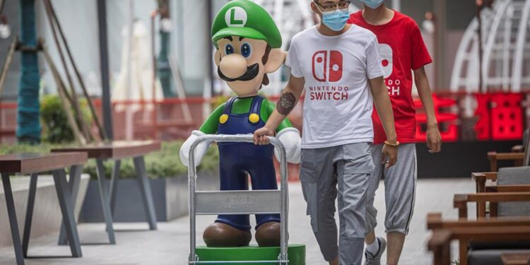 Dos hombres conducen una figura del popular Luigi, el personaje del juego de Nintendo Mario Bros juego en el centro comercial CHJ Incity en Shanghai, China. EFE/EPA/Alex Plavevski