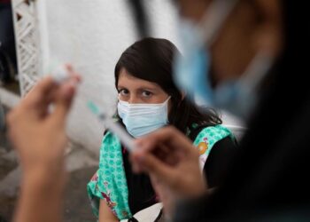 AME2413. CARACAS (VENEZUELA), 01/06/2021.- Una mujer mira como una enfermera prepara una dosis de la vacuna china Vero Cell contra la covid-19, el 28 de mayo de 2021, en el Concejo Municipal de Baruta, en Caracas. Venezuela continúa este martes en una particular contrarreloj para cumplir con la meta de vacunar al 70 % de la población, un proceso que, aparentemente, tomó relativa fuerza el fin de semana bajo un sistema segregado de "privilegios" a través del carnet de la patria impulsado por el chavismo. EFE/Rayner Peña R.