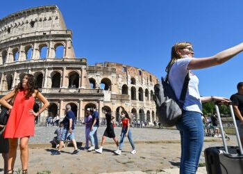 A woman takes a selfie in front of Rome's landmark Colosseum on June 12, 2021 as six more of Italy's regions and autonomous provinces will be allowed to drop most remaining Covid-19 health measures from June 14 as the latest data showed infection rates remain low nationwide. (Photo by Alberto PIZZOLI / AFP)