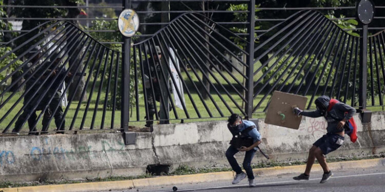 VEN10. CARACAS (VENEZUELA), 22/06/2017.- El joven David José Vallenilla (2d), de 22 años, recibe un disparo de un miembro de la Guardia Nacional Bolivariana (GNB) hoy, jueves 22 de junio de 2017, en las inmediaciones de la bases aérea militar La Carlota, en Caracas (Venezuela). El Ministerio Público (MP) de Venezuela informó hoy del fallecimiento de Vallenilla, que recibió un disparo durante una manifestación opositora en Caracas. Con este deceso la Fiscalía cuenta 75 fallecidos según los datos corregidos y actualizados del organismo en sus informes sobre la oleada de protestas que inició el pasado 1 de abril en el país. EFE/Miguel Gutiérrez