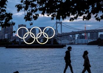 (FILES) This file photograph taken on April 28, 2021, shows a general view of the Olympic rings lit up at dusk on the Odaiba waterfront in Tokyo. - US drugs giant Pfizer and its German partner BioNTech on May 6, 2021, have announced a deal with the International Olympics Committee to provide vaccines to competitors and staff at the Tokyo games. In a statement, the firms said they would coordinate with national sporting bodies to make sure that coronavirus vaccines are available to anyone who needs one before travelling to Japan (Photo by CHARLY TRIBALLEAU / AFP)