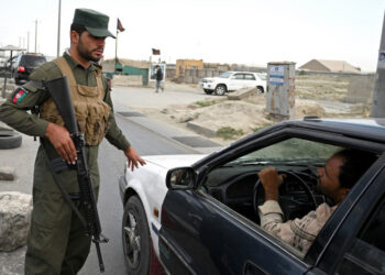 An Afghan policeman speaks to a commuter in car at a checkpoint along the road in Kabul on August 14, 2021. (Photo by WAKIL KOHSAR / AFP)