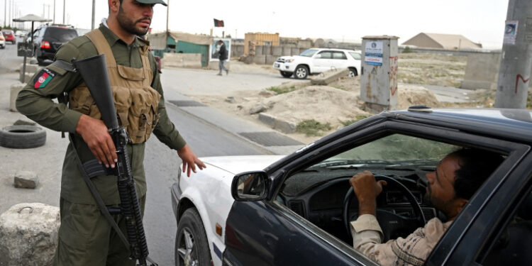 An Afghan policeman speaks to a commuter in car at a checkpoint along the road in Kabul on August 14, 2021. (Photo by WAKIL KOHSAR / AFP)