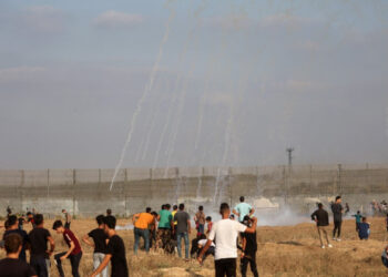 Palestinian protesters watch incoming tear gas canisters shot by Israeli security forces amid clashes following a demonstration near the border fence with Israel, east of Gaza City, to denounce the Israeli siege of the Palestinian strip and express support for Jerusalem's Al-Aqsa mosque, on August 21, 2021. - Israeli troops fired live rounds at Palestinian protesters who hurled firebombs and burned tyres from behind the Gaza Strip's border fence, with medics reporting 23 Palestinians injured. The protest called for by the Palestinian Hamas movement that rules Gaza marks the burning 52 years ago of Jerusalem's Al-Aqsa Mosque, the third-holiest site in Islam. (Photo by SAID KHATIB / AFP)