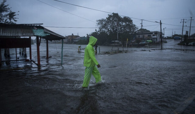 A man walks in a flooded street due to heavy rains caused by Hurricane Grace in Tecolutla, Veracruz, Mexico, on August 21, 2021. - Hurricane Grace lashed eastern Mexico with heavy rain and strong wind on Saturday, causing flooding, power blackouts and damage to homes as it gradually lost strength over the mountainous interior. (Photo by VICTORIA RAZO / AFP)