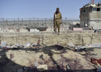 A Taliban fighter stands guard at the site of the August 26 twin suicide bombs, which killed scores of people including 13 US troops, at Kabul airport on August 27, 2021. (Photo by WAKIL KOHSAR / AFP)