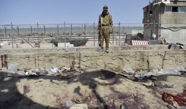 A Taliban fighter stands guard at the site of the August 26 twin suicide bombs, which killed scores of people including 13 US troops, at Kabul airport on August 27, 2021. (Photo by WAKIL KOHSAR / AFP)