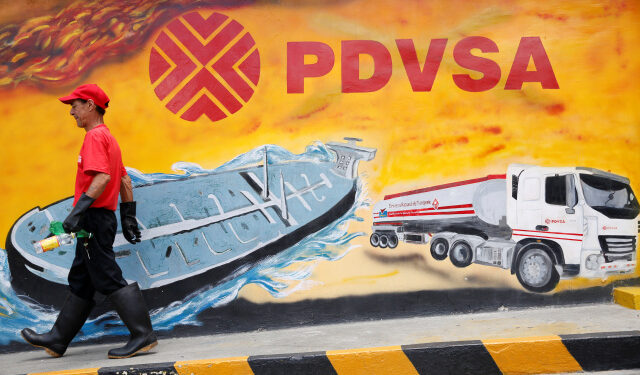 Imagen de archivo de un trabajador pasando junto a un mural de PDVSA en una gasolinera de Caracas. 29 agosto 2014. REUTERS/Carlos Garcia Rawlins