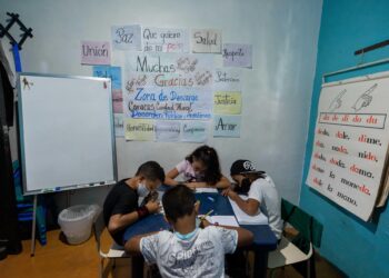 Niños hacen tareas durante una clase en la casa de la maestra Jasmín Castro, el 20 de agosto de 2021, en Petare, Caracas (Venezuela). Maestras preocupadas por la educación de los niños que habitan en Petare, una de las barriadas más pobres de Venezuela, abrieron las puertas de sus casas para educar a los chicos en medio del cierre de escuelas, empujado por la covid-19, que ya suma más de un año y el difícil acceso a internet. EFE/ RAYNER PEÑA R.