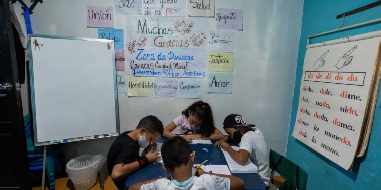 Niños hacen tareas durante una clase en la casa de la maestra Jasmín Castro, el 20 de agosto de 2021, en Petare, Caracas (Venezuela). Maestras preocupadas por la educación de los niños que habitan en Petare, una de las barriadas más pobres de Venezuela, abrieron las puertas de sus casas para educar a los chicos en medio del cierre de escuelas, empujado por la covid-19, que ya suma más de un año y el difícil acceso a internet. EFE/ RAYNER PEÑA R.