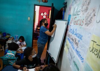 La maestra Jasmín Castro escribe en una pizarra durante una clase en su casa, el 20 de agosto de 2021, en Petare, Caracas (Venezuela). Maestras preocupadas por la educación de los niños que habitan en Petare, una de las barriadas más pobres de Venezuela, abrieron las puertas de sus casas para educar a los chicos en medio del cierre de escuelas, empujado por la covid-19, que ya suma más de un año y el difícil acceso a internet. EFE/ RAYNER PEÑA R.