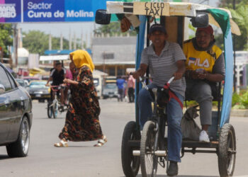 A man rides a traditional tricycle taxi in Maracaibo, Zulia State, Venezuela, on July 29, 2021. - Franklin relies on the wind to power his small sailboat. Manuel, a former bus driver, carries passengers in a "bicitaxi". Both manage to survive the chronic fuel shortages in Zulia, the region that saw the birth of Venezuela's oil industry. (Photo by Luis BRAVO / AFP)