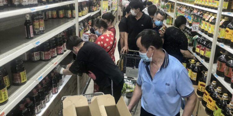 This photo taken on August 2, 2021 shows people buying items at a supermarket in Wuhan, in China's central Hubei province, as authorities said they would test its entire population for Covid-19 after the central Chinese city where the coronavirus emerged reported its first local infections in more than a year. (Photo by STR / AFP) / China OUT