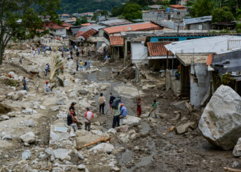 Residents are seen in an area where several homes were destroyed by a mudslide caused by heavy rains in Valle del Mocoties community, municipality of Tovar, Merida state, Venezuela on August 26, 2021. - The death toll from heavy rains that triggered mudslides and floods in western Venezuela has risen to 20, local authorities said Wednesday, with 17 other people missing. Nine states are in an "emergency" situation and more than 54,000 people have been affected by the downpours, Interior Minister Remigio Ceballos told state television. (Photo by Miguel Zambrano / AFP)