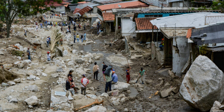 Residents are seen in an area where several homes were destroyed by a mudslide caused by heavy rains in Valle del Mocoties community, municipality of Tovar, Merida state, Venezuela on August 26, 2021. - The death toll from heavy rains that triggered mudslides and floods in western Venezuela has risen to 20, local authorities said Wednesday, with 17 other people missing. Nine states are in an "emergency" situation and more than 54,000 people have been affected by the downpours, Interior Minister Remigio Ceballos told state television. (Photo by Miguel Zambrano / AFP)
