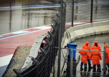 Personal del circuito de Sochi charla bajo la lluvia tras la suspensión de los terceros ensayos libres del Gran Premio de Rusia de Fórmula 1, el 25 de septiembre de 2021. Foto AFP.
