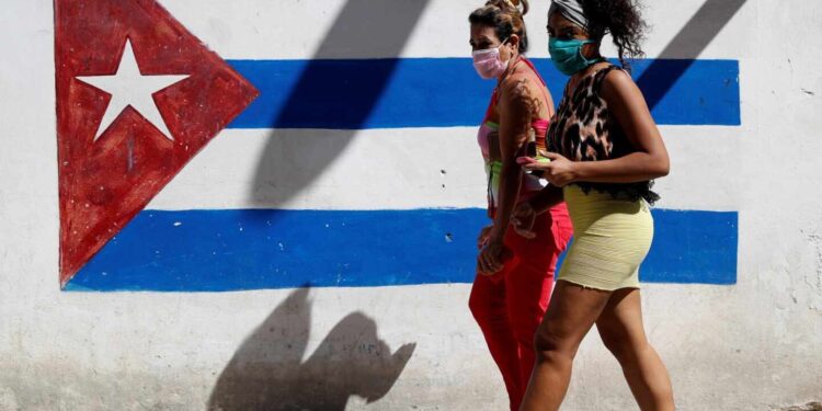 -FOTODELDÍA- HAB101. HABANA (CUBA), 02/04/2020.- Dos mujeres caminan frente a un graffiti de la bandera cubana, este jueves en La Habana (Cuba). El gobierno confirmó 21 nuevos casos positivos a la Covid-19 y llega a un total de 233 infectados. EFE/Yander Zamora