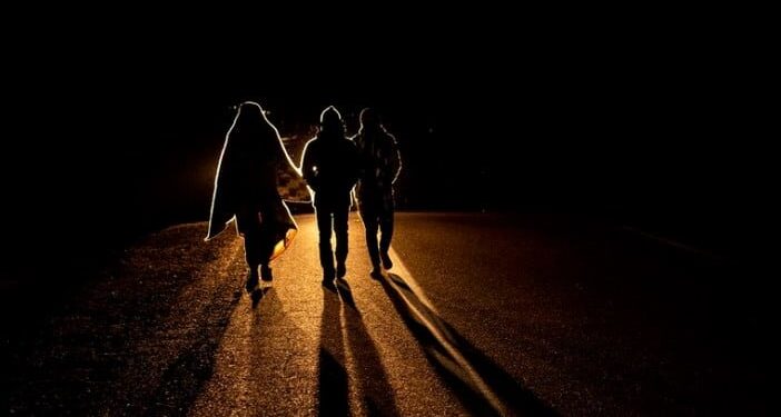 Venezuelan migrant Rubi Alexander G. (L) and friends walk under cold temperatures at night along the highway that links Colchane with Iquique, after crossing from Bolivia, in Huara, Chile, on February 17, 2021. - Crossing the highlands of the border between Bolivia and Chile on foot is the hardest part of the journey Venezuelan migrants go through on their way to Iquique or Santiago. (Photo by MARTIN BERNETTI / AFP)