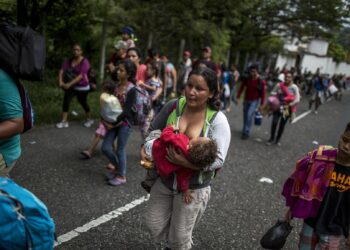 Dilsia Castellana, 34, originaria de San Pedro Sula, da pecho a su hijo Agner, de 13 meses, mientras camina por la carretera hacia Chiquimula, junto con sus otros dos hijos de 10 y 12 años