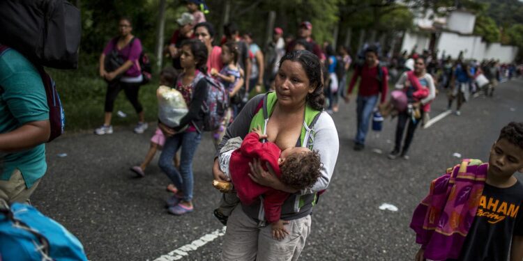 Dilsia Castellana, 34, originaria de San Pedro Sula, da pecho a su hijo Agner, de 13 meses, mientras camina por la carretera hacia Chiquimula, junto con sus otros dos hijos de 10 y 12 años