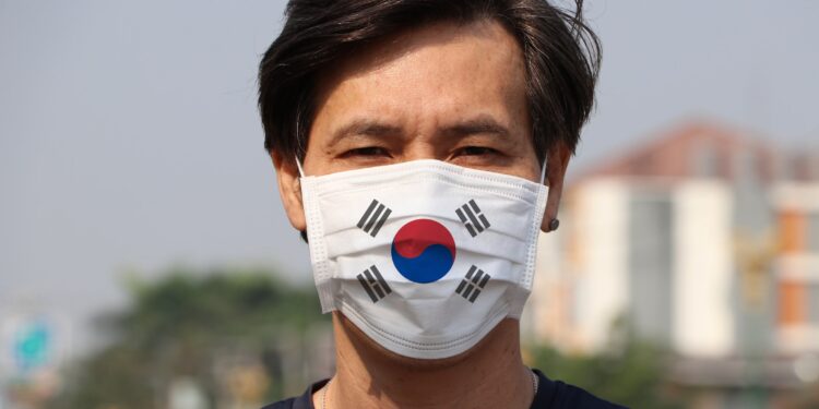 South Korea flag on hygienic mask. Masked Asian man prevent germs. concept of Tiny Particle protection or virus corona.