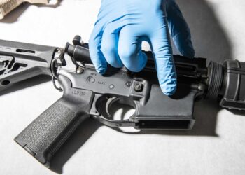 A police service technician with the Oakland Police Department Property and Evidence Unit points to a seized AR-15 assault rifle from a sample of ghost guns, or unregistered and untraceable firearms, at the department's headquarters in Oakland, California Thursday, April 15, 2021.