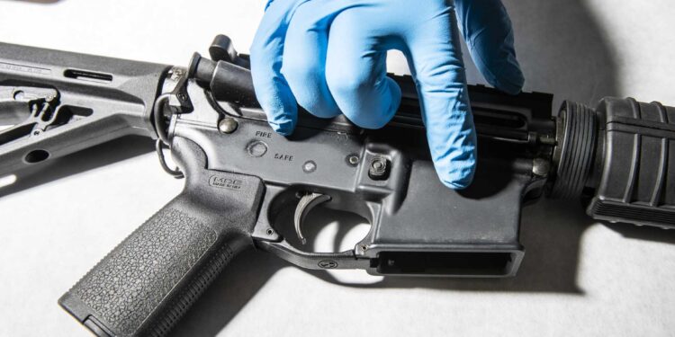 A police service technician with the Oakland Police Department Property and Evidence Unit points to a seized AR-15 assault rifle from a sample of ghost guns, or unregistered and untraceable firearms, at the department's headquarters in Oakland, California Thursday, April 15, 2021.