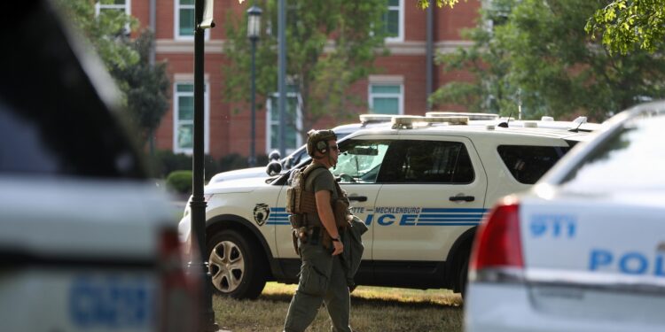 A medic walks between police cars after a shooting on the campus of University of North Carolina Charlotte in University City, Charlotte, on April 30, 2019. - Six people were shot, two of them died on the University of North Carolina Charlotte campus. One person was taken into custody, according to police sources. (Photo by Logan Cyrus / AFP)