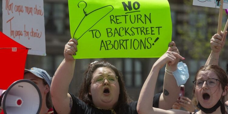 Pro-choice counter-protesters hold signs on the sidelines of the pro-life National March for Life in Ottawa, Ontario, on May 12, 2022. - The protest comes amid a political firestorm in the United States ignited by a leaked draft opinion that showed the Supreme Court's conservative majority preparing to overturn Roe v. Wade, a landmark 1973 ruling guaranteeing abortion access nationwide. (Photo by Lars Hagberg / AFP)