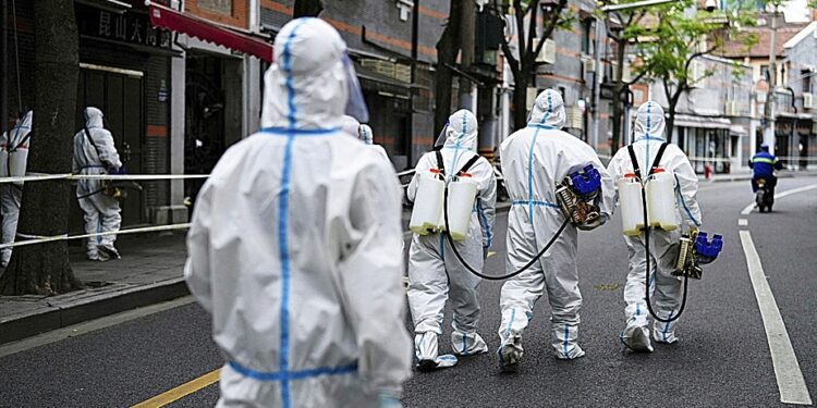 Workers in protective suits disinfect an old residential area under lockdown amid the coronavirus disease (COVID-19) pandemic, in Shanghai, China, April 15, 2022. REUTERS/Aly Song