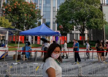 Una mujer pasa frente a una alineación de personas que esperan para someterse a una prueba COVID-19 en Pekín, China. EFE/EPA/MARK R. CRISTINO
