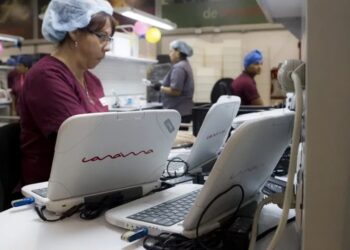 Trabajadores de la industria Canaima ensamblan computadores portátiles. Foto EFE.