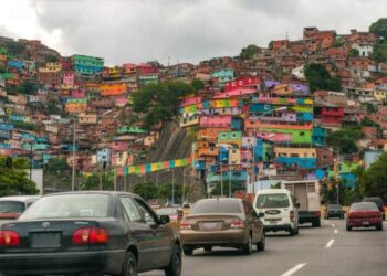 Photograph taken in Caracas, Venezuela, on September 2, 2015 where you can see a high traffic road with many vehicles being hours of noon. You see the white streaks on the asphalt, the road public lighting and on the sides a great overcrowding of very colorful popular housing or more commonly called "ranchos" whose characteristics of poverty do not allow them to have all the comforts and security of a standard home.