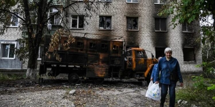 Dos mujeres pasan por delante de una residencia destruida en Balakliya, región de Kharkiv, el 17 de septiembre de 2022, en medio de la invasión rusa de Ucrania. (Foto de Juan BARRETO / AFP)