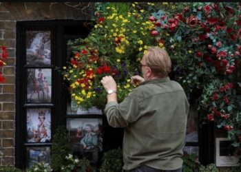 Un vecino de Windsor arregla las plantas, junto a fotos de la reina Isabel de Gran Bretaña, tras su muerte, en Windsor, Gran Bretaña, el 15 de septiembre de 2022. REUTERS/Paul Childs